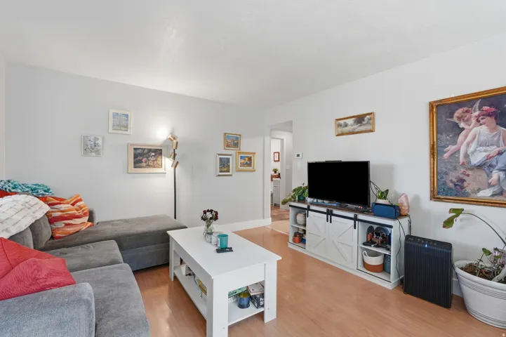 [Unit 1] Bright and inviting living space featuring sleek wood-look flooring, neutral paint, and an open layout with excellent natural light.