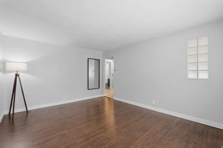 [Unit 3] Open living space highlighting durable wood-grain flooring, accent glass block window detailing, and easy flow into adjacent rooms.