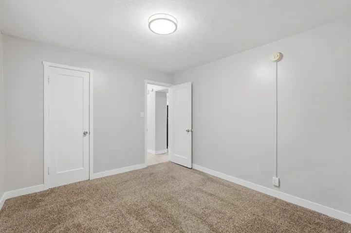[Unit 3] Bedroom view highlighting soft carpeting, neutral palette, bright flush-mount ceiling fixture, and dedicated closet space.