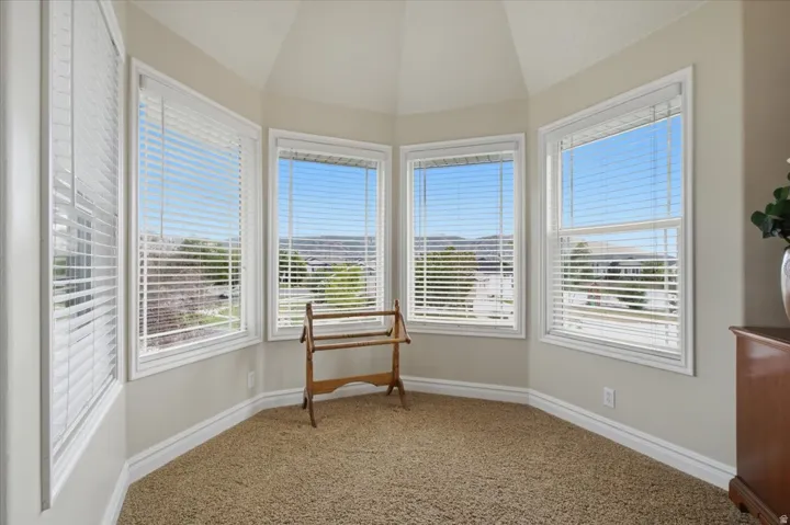 Primary Suite, Bay window with multiple windows, white window blinds, light-colored walls, and textured carpeting