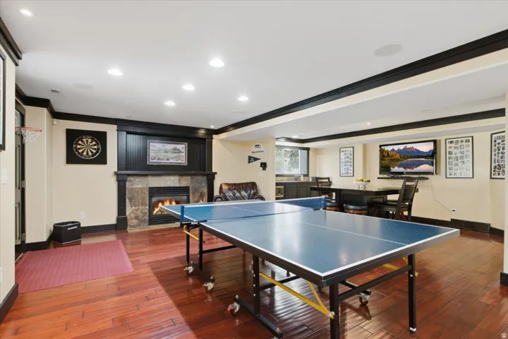 Stone-clad fireplace with wood surround, polished wood flooring, recessed lighting, built-in cabinetry, and integrated ceiling speakers
