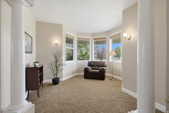 Carpeted room with a bay window, two decorative columns, and two wall-mounted sconces