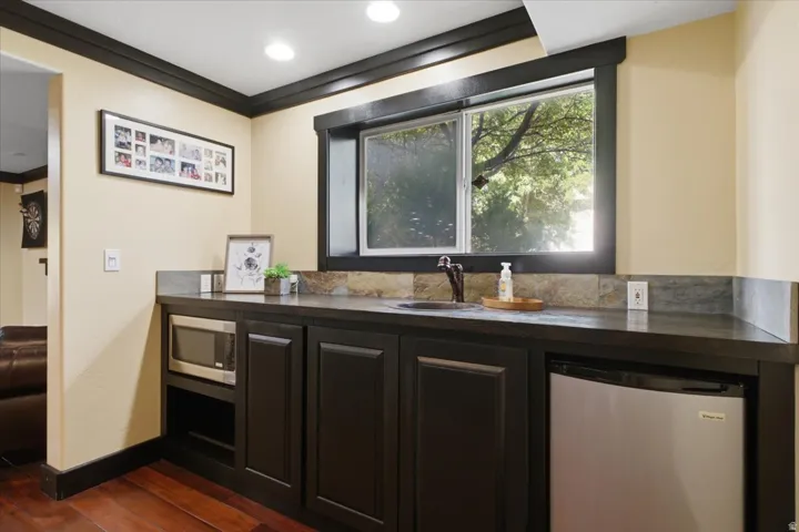 Built-in cabinetry with dark finishes, integrated stainless steel mini-refrigerator, under-cabinet microwave, and a dark basin sink