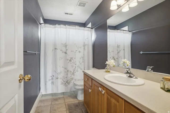 Bathroom featuring a wood-finish vanity with an integrated sink, a large mirror, and tile flooring