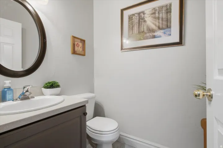 Bathroom featuring a single vanity, undermount sink, wall-mounted mirror, and white toilet
