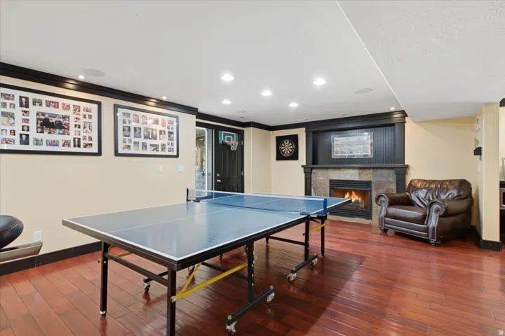 Hardwood-finish flooring, recessed lighting, and a stone-clad fireplace with a dark wood mantel