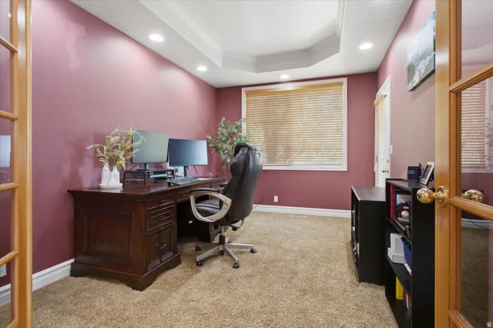 Recessed lighting, tray ceiling, French doors with glass panels, large window with blinds, and wall-to-wall carpeting