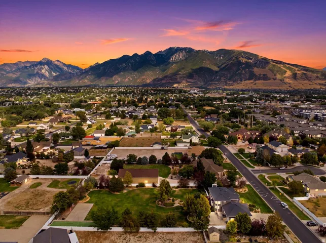 Expansive neighborhood setting with established homes and mature trees, featuring paved roads and mountain scenery
