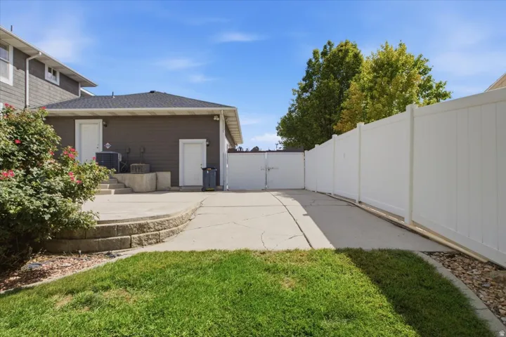 Paved driveway with a secure gated entry, leading to a concrete patio and a retaining wall