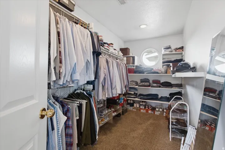 Primary Suite Walk-in closet with carpet flooring, built-in shelving, and a circular window