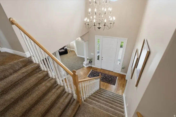Two-story foyer with a decorative chandelier, light wood-finish flooring, and a white paneled entry door with sidelights