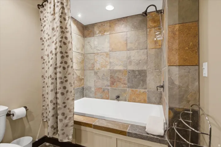 Built-in bathtub with multi-toned stone tile surround and walls