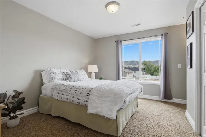 Carpeted room with a large window, neutral wall paint, and a semi-flush mount ceiling light fixture