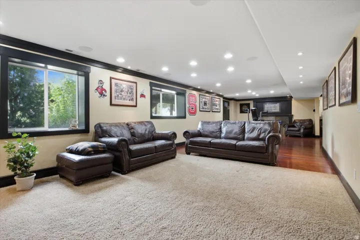 Recessed lighting, wood-finish flooring, two large windows, white ceiling, and a large carpeted area