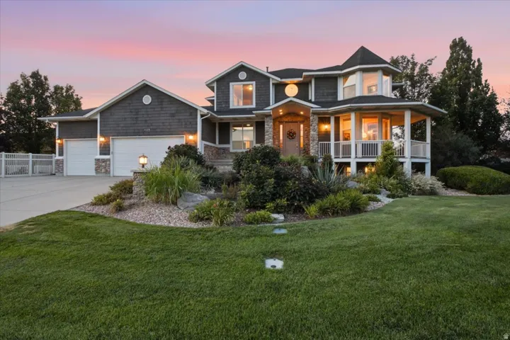 Exterior featuring stone accents, dark shake siding, a multi-car garage, a covered front entry, and a covered porch with white railings