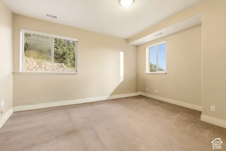 Daylight level bedroom with south and west view.   Plush carpeting, neutral wall tones, and white trim