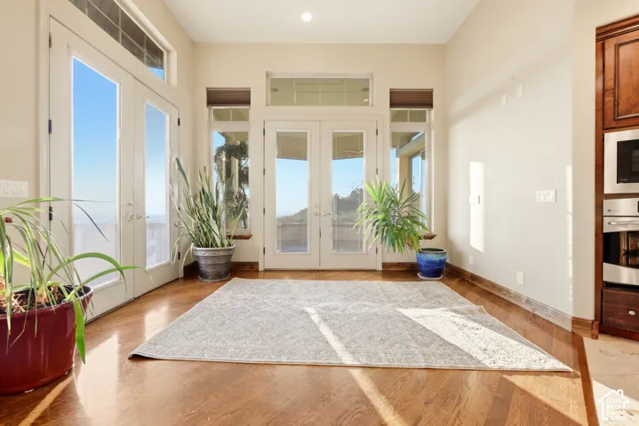 Hardwood flooring, recessed ceiling lighting, built-in wall oven and microwave, French doors with transom windows, and an additional French door with transom windows
