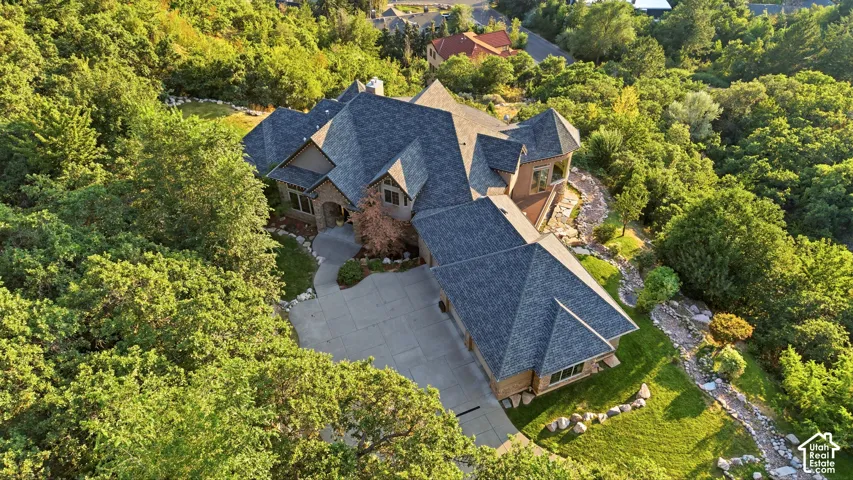 Expansive property featuring a multi-gabled roofline, stone and wood-finish siding, a paved driveway, and established landscaping