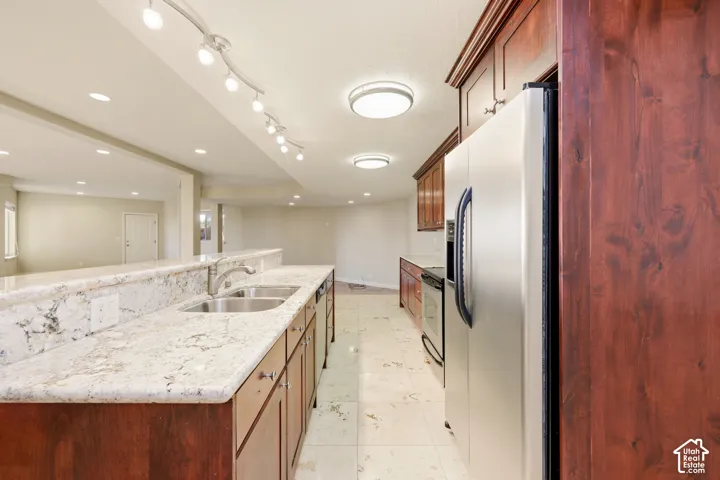 Kitchen featuring a dual basin sink with a chrome faucet, light-toned stone countertops, and wood cabinetry