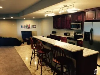 Kitchenette featuring a stainless steel refrigerator, built-in microwave, dark wood cabinetry, and light-colored countertops