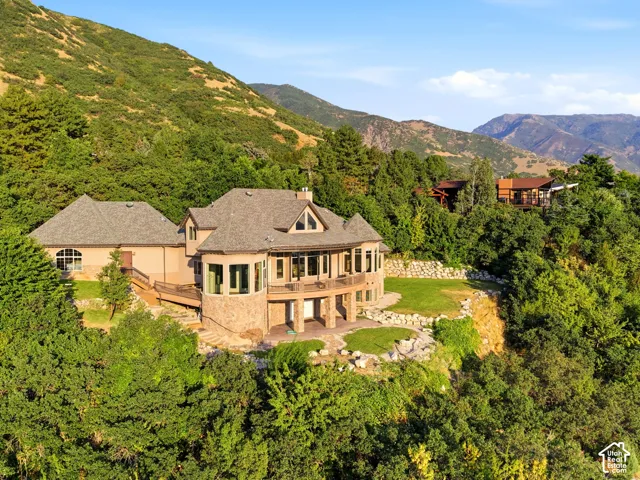 Stone-clad exterior with multiple balconies, a multi-pitch roof, and an expansive deck