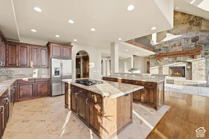 Gourmet kitchen featuring wood cabinetry, stainless steel refrigerator, and granite countertops