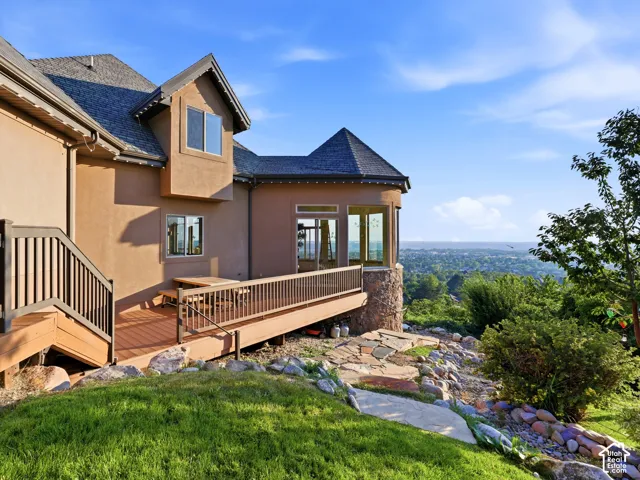 Multi-level composite deck with dark railings, stucco exterior, stone accents, and a turret structure