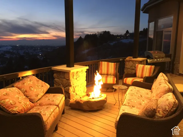 Expansive deck featuring wood-finish flooring, stone-clad pillars, and a built-in outdoor grill
