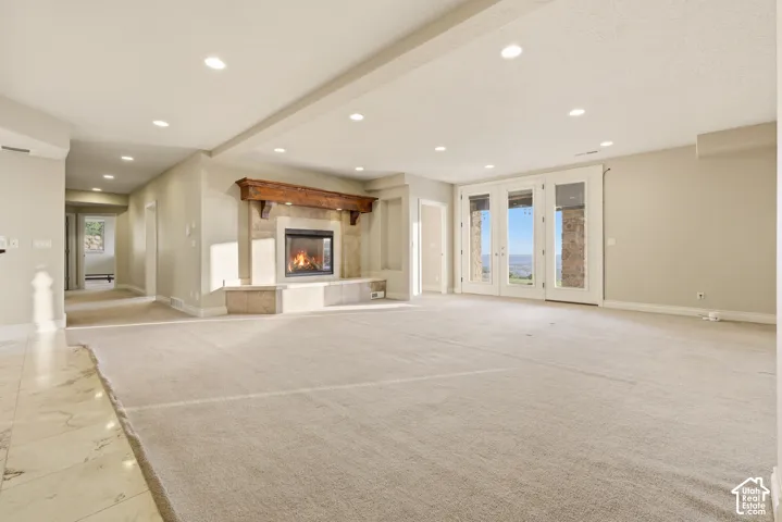 Spacious room featuring a stone fireplace with a wood mantle, recessed lighting, and light-colored carpeting