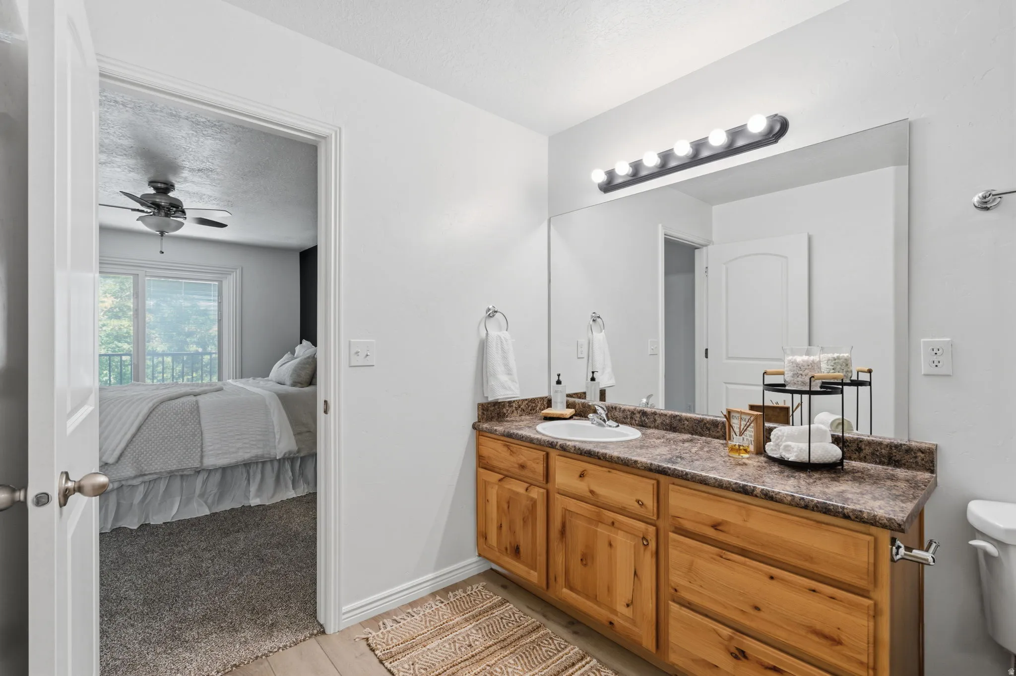 Bathroom vanity with a single basin sink, wood-finish cabinetry, and a large wall-mounted mirror