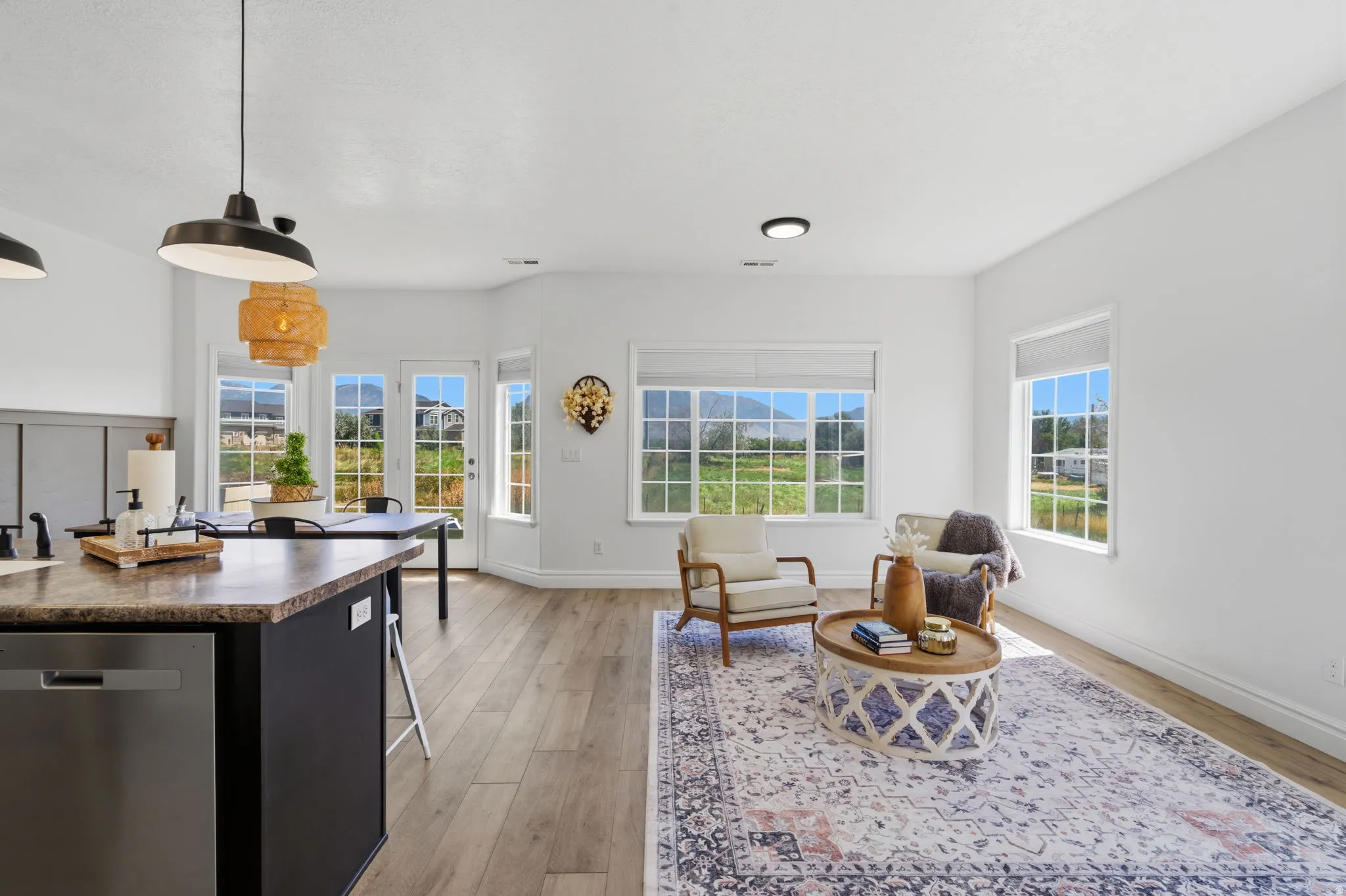 Open-concept interior featuring wood-finish flooring, white walls, and abundant natural light from multiple windows