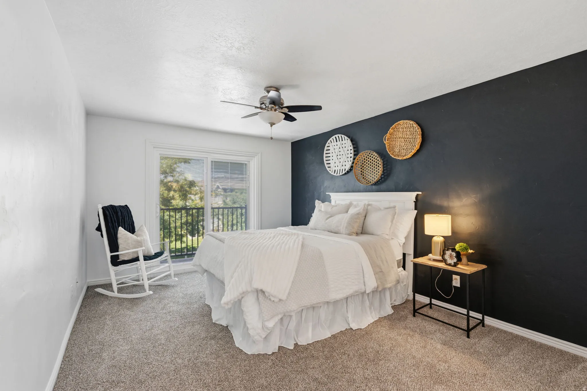 Sliding glass door leading to a balcony, ceiling fan, and carpeted flooring