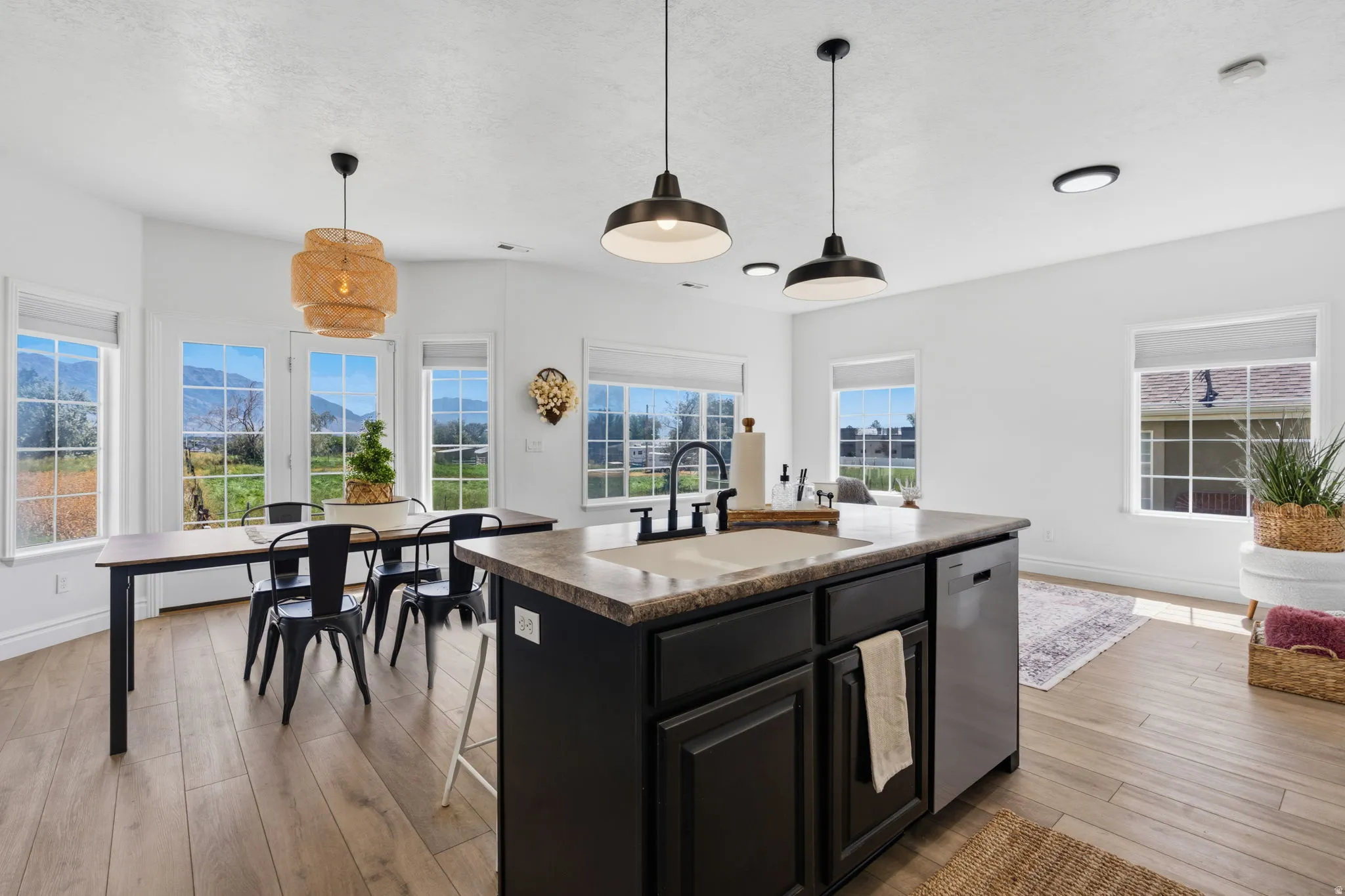Central island with integrated sink, wood-finish flooring, multiple windows, and a dining area