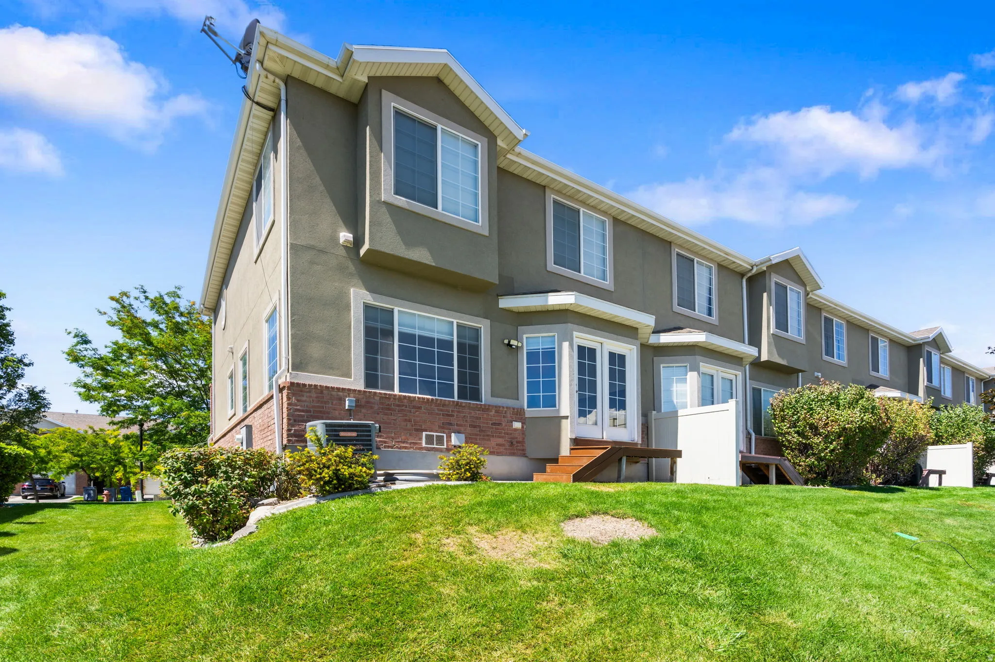 Rear exterior featuring stucco siding, brick detailing, and multiple windows