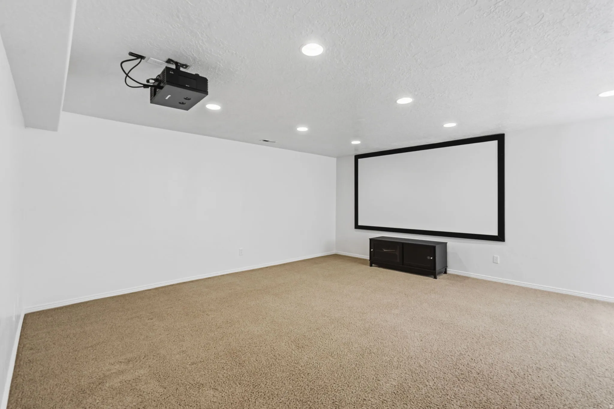 Theater room featuring a mounted projector, large projection screen, recessed lighting, and carpet flooring