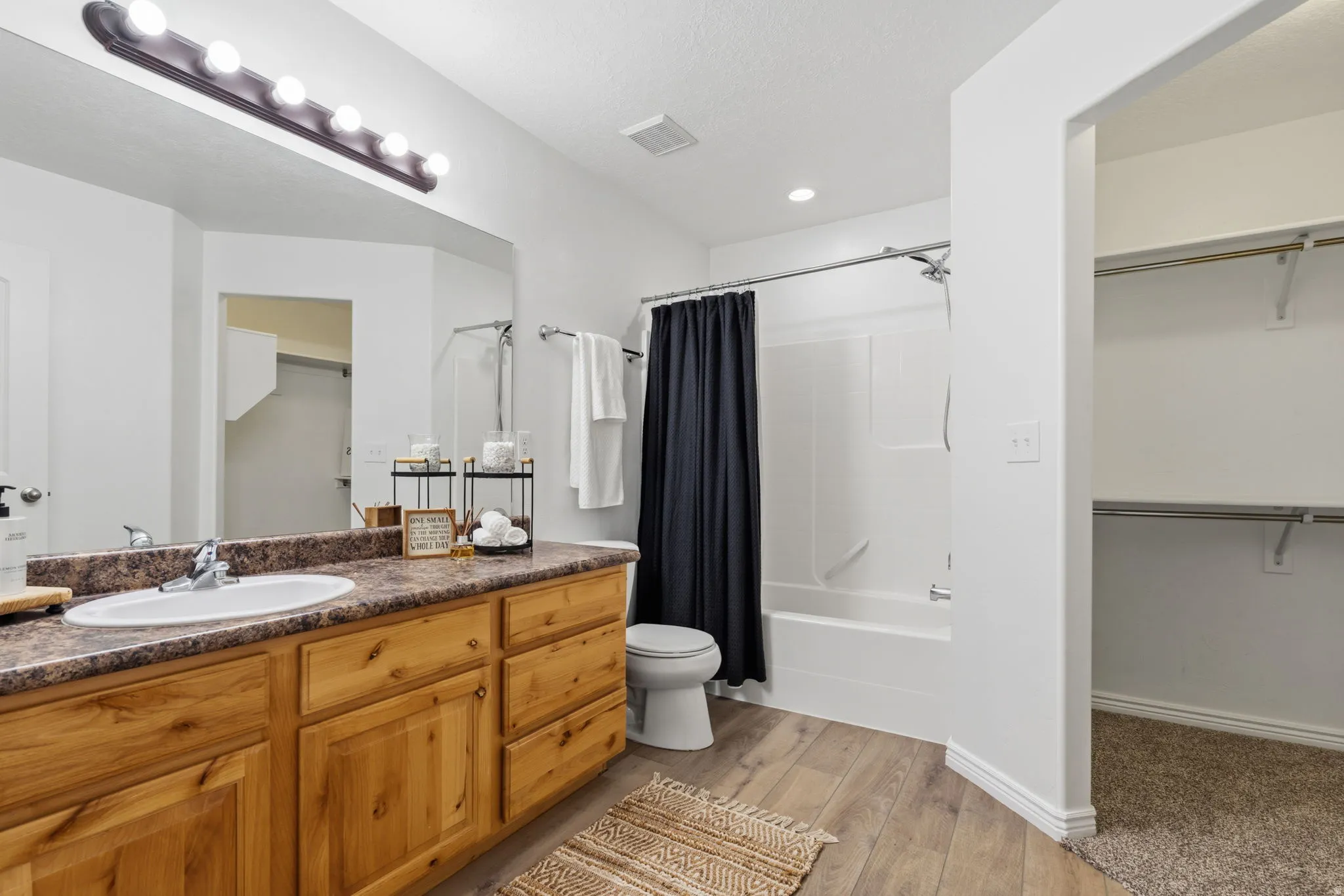 Vanity with wood-finish cabinetry, integrated sink, and vanity lighting