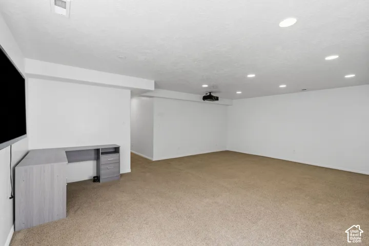 Spacious room featuring neutral carpeting, recessed lighting, and a mounted projector