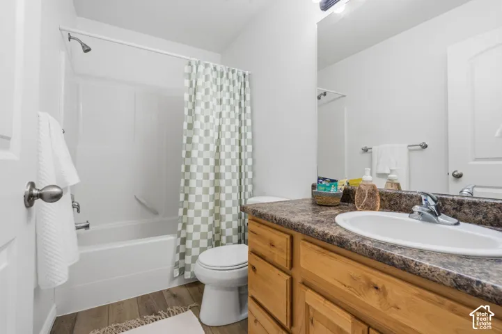 Wood-finish flooring, single vanity with a laminate countertop, and a shower-tub combination