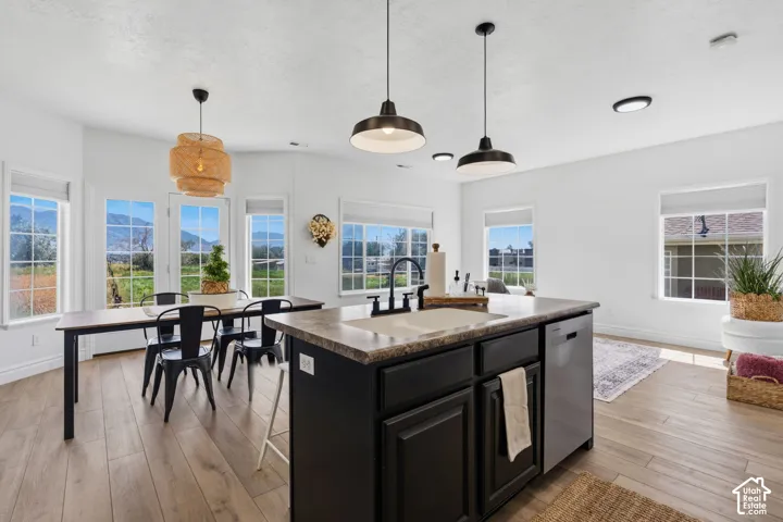 Central island with integrated sink, wood-finish flooring, multiple windows, and a dining area