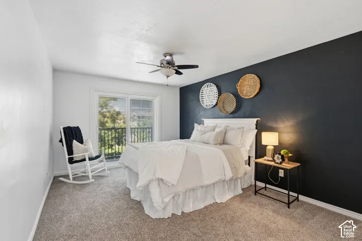 Sliding glass door leading to a balcony, ceiling fan, and carpeted flooring