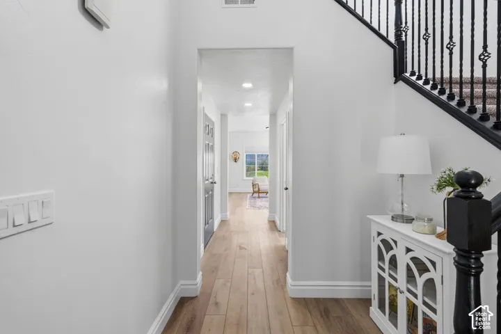 Wood-finish flooring throughout, white baseboards, and a black staircase with decorative iron balusters