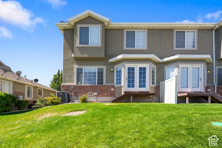 Exterior featuring a multi-level design, multiple windows, double French doors, and a lower-level brick facade