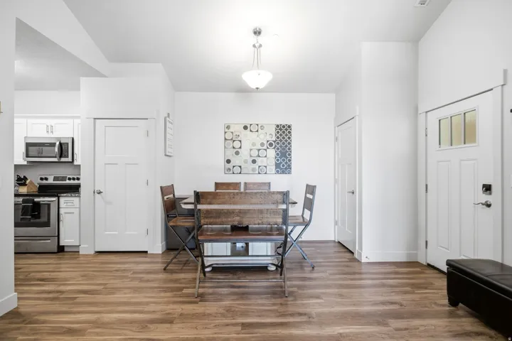 Wood-finish flooring throughout, white shaker-style cabinetry, stainless steel appliances, and a ceiling-mounted light fixture
