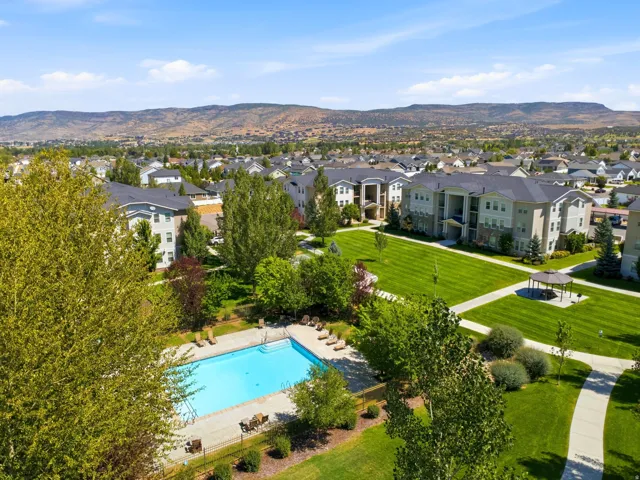 Outdoor swimming pool with surrounding lounge chairs, expansive green lawns, paved walkways, and a covered gazebo