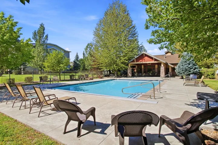 Expansive outdoor pool with a surrounding concrete deck, complemented by a nearby building featuring stone accents and a covered entry