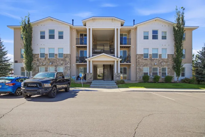 Multi-story building featuring stone accents, white horizontal siding, and multiple balconies