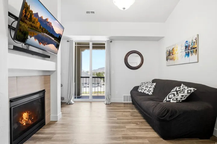 Wood-finish flooring, built-in fireplace with a hearth, white walls, and sliding glass doors to outdoor space