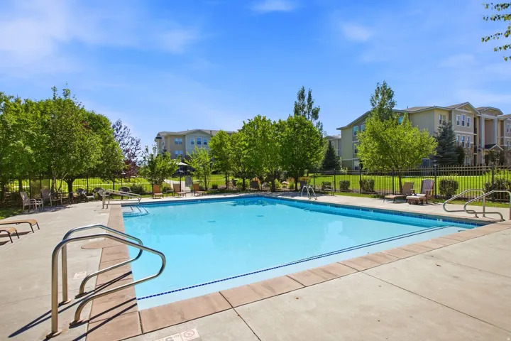 Outdoor swimming pool featuring a concrete deck and metal handrails