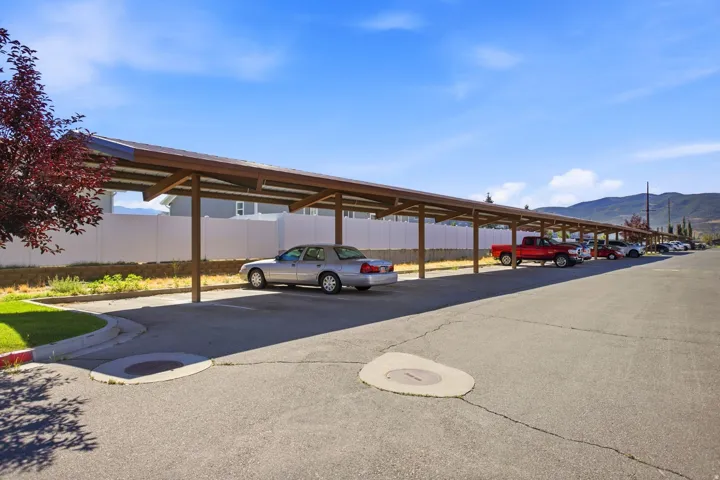 Covered parking structure with multiple spaces, asphalt lot, and perimeter fencing