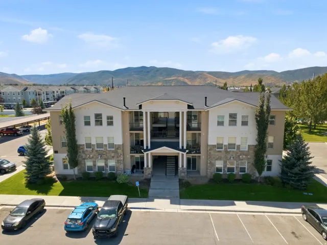 Multi-story building featuring a pitched roof, exterior balconies, and a stone and stucco facade